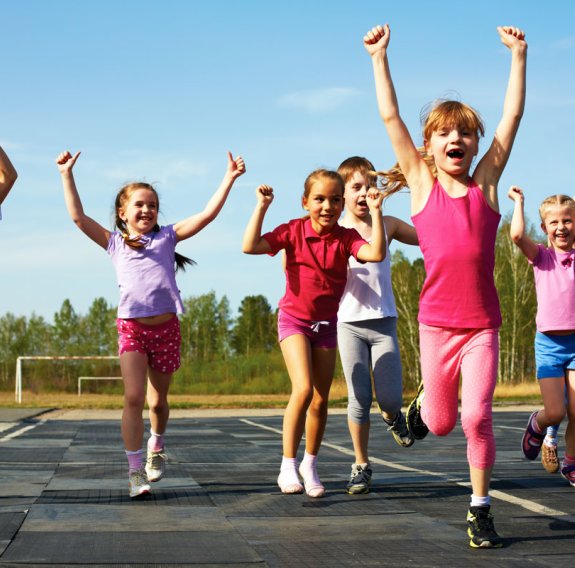 Lachende Kinder laufen über eine Laufstrecke