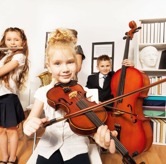Ein Mädchen mit Geige, ein Mädchen mit Querflöte und ein Junge mit Kontrabass