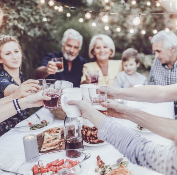 Menschen die gemeinsam am Tisch anstoßen