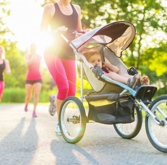 Mama mit ihrem Baby im Kinderwagen übt Sport aus